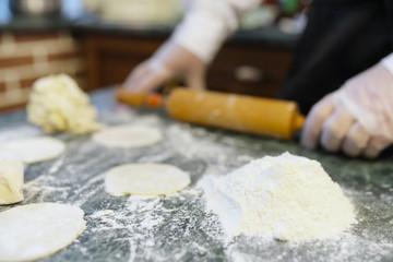 Male chef uses ingredients for preparing flour products on kitchen table