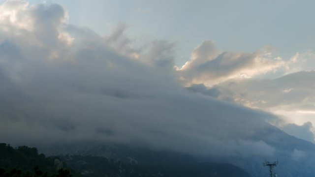 Timelapse clouds fly near the top of the mountains