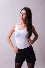 Beautiful lady in white shirt and black shorts on gray background. Sexy lady. Perfect beautiful attractive female posing in model test in studio