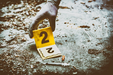 Putting the crime scene marker on the ground next to syringe