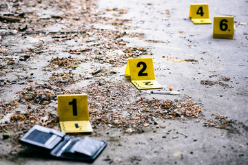 Crime investigation, yellow crime scene marker next to the wallet on the ground