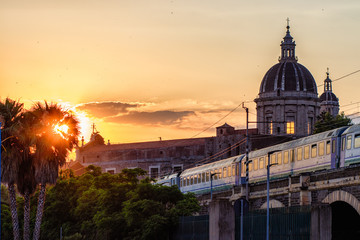 Catania, passing the train at sunset over the marina arches (archi della marina). View of the...