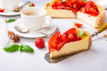 Piece of delicious homemade strawberry cheesecake and flowers on gray stone background. Selective focus.