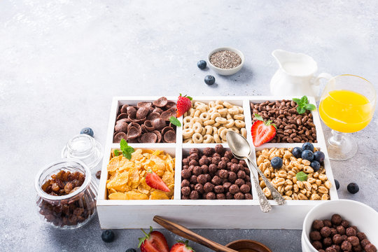 Variety of cold quick breakfast cereals with berries in white wooden box, healthy eating for kids, selective focus.