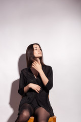 Beautiful sensual woman on a chair in studio on gray background. Sexy lady. Perfect beautiful attractive female posing in model test in studio