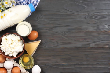 Glass jug pitcher of fresh milk with glass, eggs and cottage cheese in a rustic setting on the wooden background  with copy space. Top view.