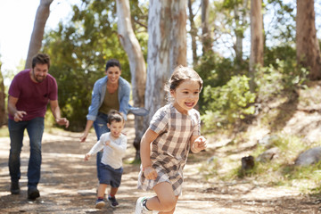 Fototapeta premium Family Running Along Path Through Forest Together