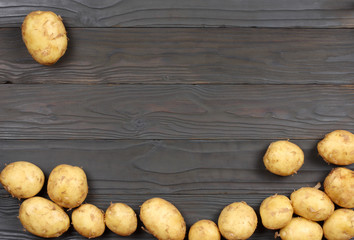 Raw potato on wooden background. Top view with copy space.