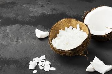 Half of ripe coconut and coconut shavings on a dark background. Copy space. Food background