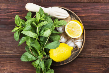 Ingredients for lemonade - lemon, mint, ice in wooden tray on a wooden background. Top view. Food background