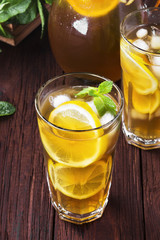 Ice tea with lemon and mint on a wooden background