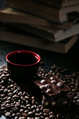 coffee cup and coffee beans and chocolate on the background of books