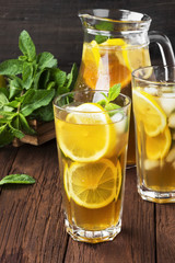 Ice tea with lemon and mint on a wooden background