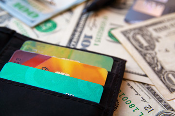 One hundred dollars bills and credit cards in black leather pocket, close-up view.