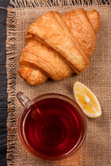 croissant with a cup of tea on sackcloth. Top view