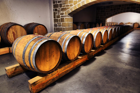 Wine barrels and metal cisterns in dark cellar