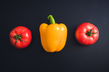 Yellow pepper, red tomatoes, black salt, black background,Ingredients for Vegetarian Food