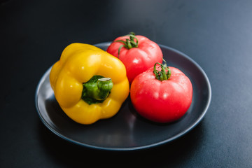 Yellow pepper, red tomatoes, black salt, black background,Ingredients for Vegetarian Food