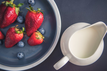 Healthy food. A bottle of milk with strawberries and blueberries on a plate with a black...