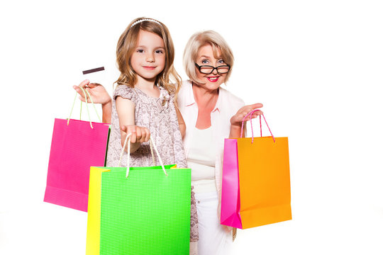 Elderly woman with granddaughter on a white background with shopping bags and a bank card