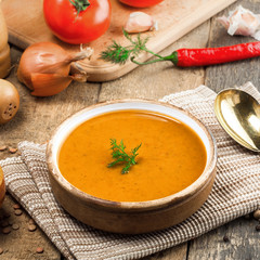 Lentil soup in a rustic bowl on a cotton canvas tablecloth. Healthy vegetarian food on an old wooden table. Top view.
