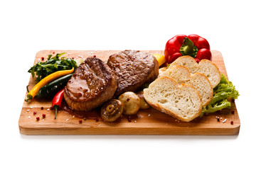 Grilled beefsteak with toasts on wooden board on white background