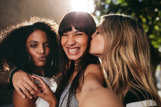 Smiling female friends hanging out together and taking selfie