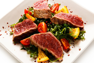 Fillet mignon - grilled beefsteaks with vegetables on white background