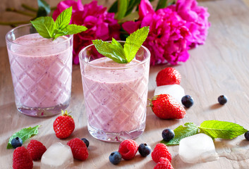 Tasty blueberry, strawberry, raspberry and yogurt smoothies with berries and mint around on wooden background
