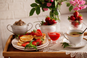 Syrniki with strawberry and green tea cup on a light background