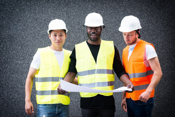 Three construction workers holding blue prints