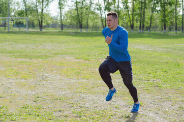 Young athlete runs along the green field