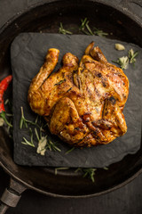 Whole corn chicken on dark pan. Restaurant. Top view © indigolt