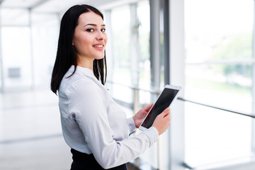 Fototapeta premium Beauitful business woman standing and looking in camera while holding tablet