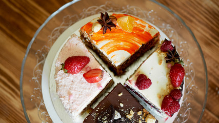The different pieces of the cake smoothly rotate on the base.There is chocolate, carrot, yogurt and berries.