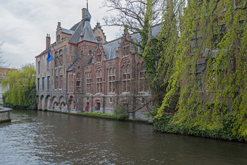 Picturesque old town of Bruges (Brugge) with brick buildings and spring trees above canal , Belgium