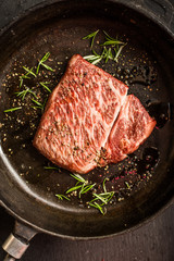 Close up raw wagyu beef striploin steak with pepper on dark pan. Restaurant