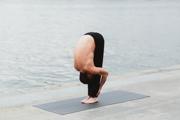 a young man practicing yoga asanas in the city on the waterfront