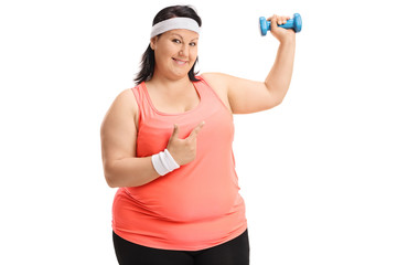 Fototapeta na wymiar Overweight woman lifting a small dumbbell and pointing