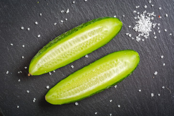 Fresh green sliced cucumber on a black stone background.