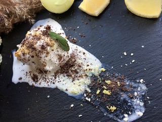 Melted white ice cream with lemon on a black tray with chocolate chips