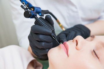 Cosmetologist applying permanent makeup on lips