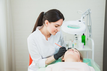 Cosmetologist applying permanent makeup with tattoo pen