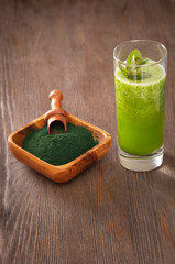 Green smoothie with spirulina on wood background