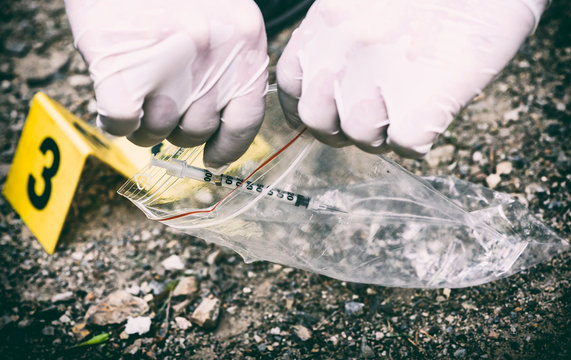 Crime scene investigation, picking up the tossed syringe and putting it to the plastic bag