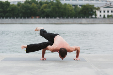 a young man practicing yoga asanas in the city on the waterfront