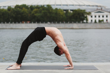 a young man practicing yoga asanas in the city on the waterfront