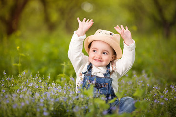 A little girl sitting in the garden and sniffs flowers, emotions, joy