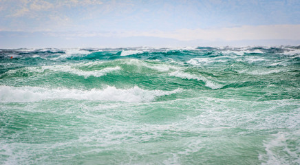 Strong wind, sea waves and the coast or beach.