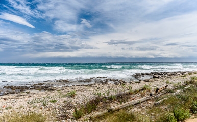 Strong wind, sea waves and the coast or beach.